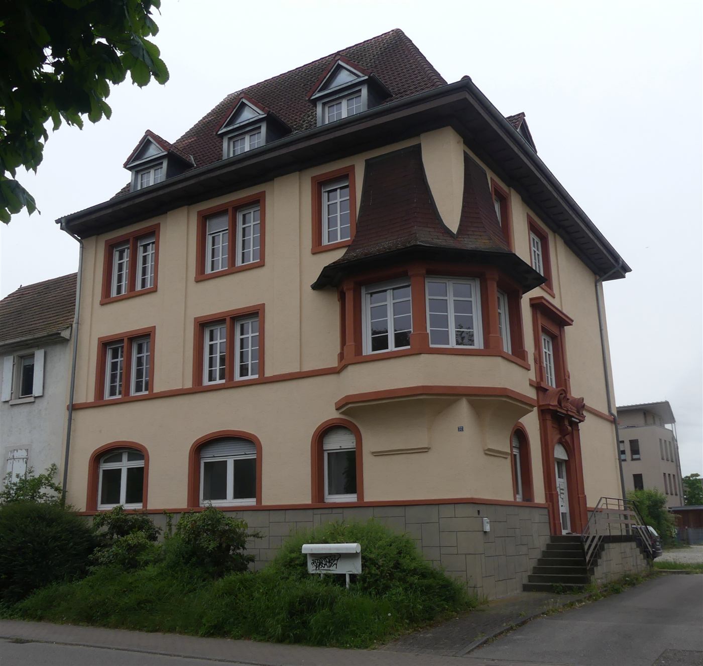 Die Friedrichstraße 32 heute: ockerfarbene Fassade mit roten Fenstergewänden, Erker und Walmdach mit Gauben
