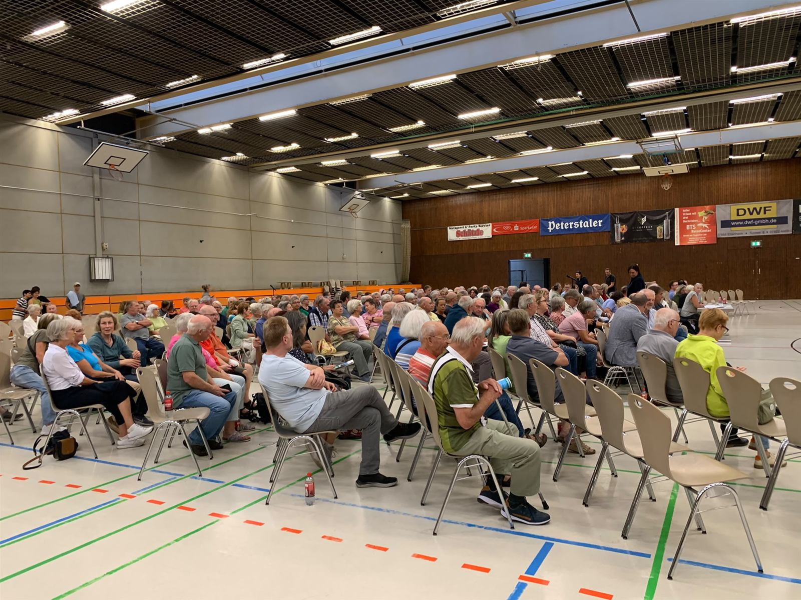 Zuhörerinnen und Zuhörer auf Stuhlreihen in der Halle vor Beginn des Informationsabends