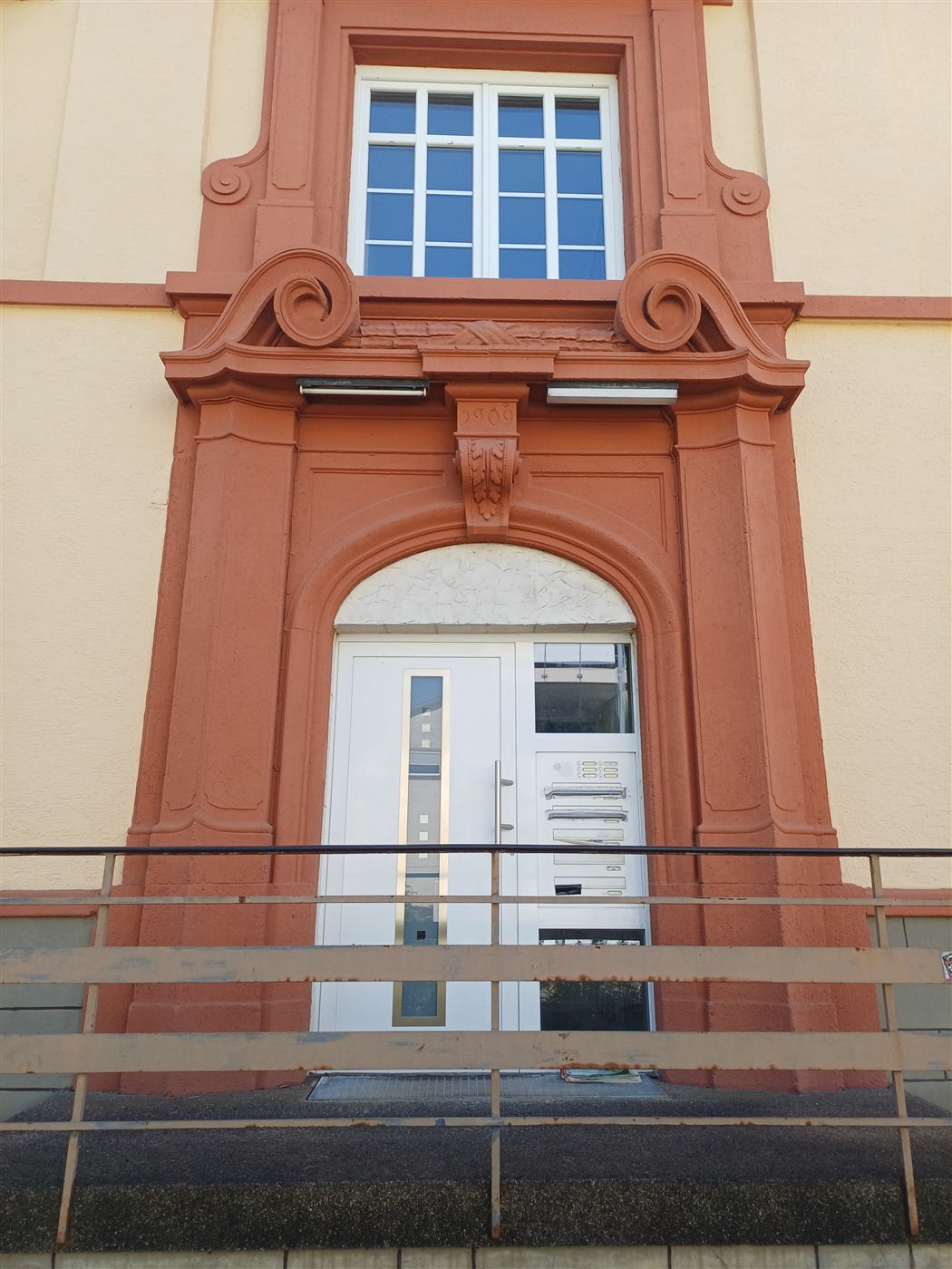 Rotes Sandstein-Portal mit Voluten und der Jahreszahl 1909 über dem Eingang